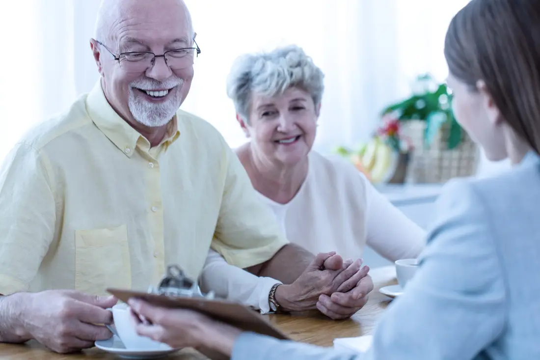 Older couple smiling as they go through papers with an adviser
