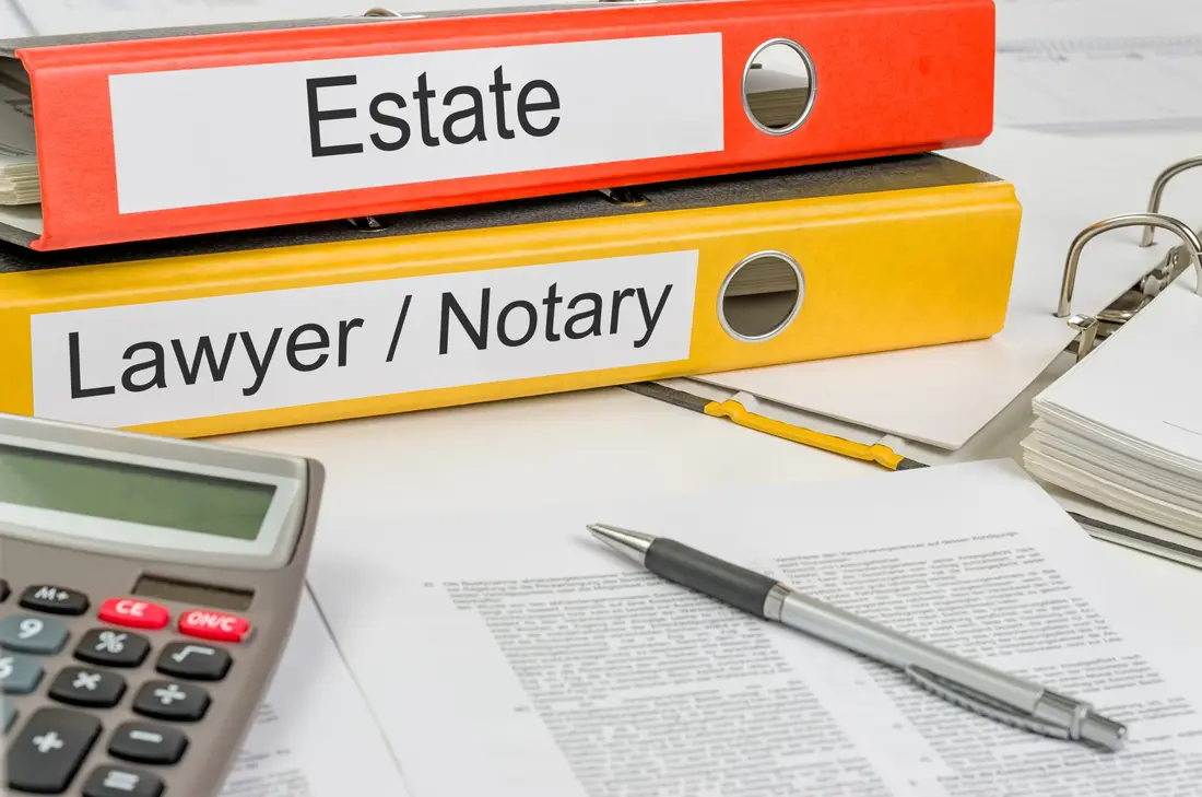 Folders labelled estate and lawyer beside a calculator and papers