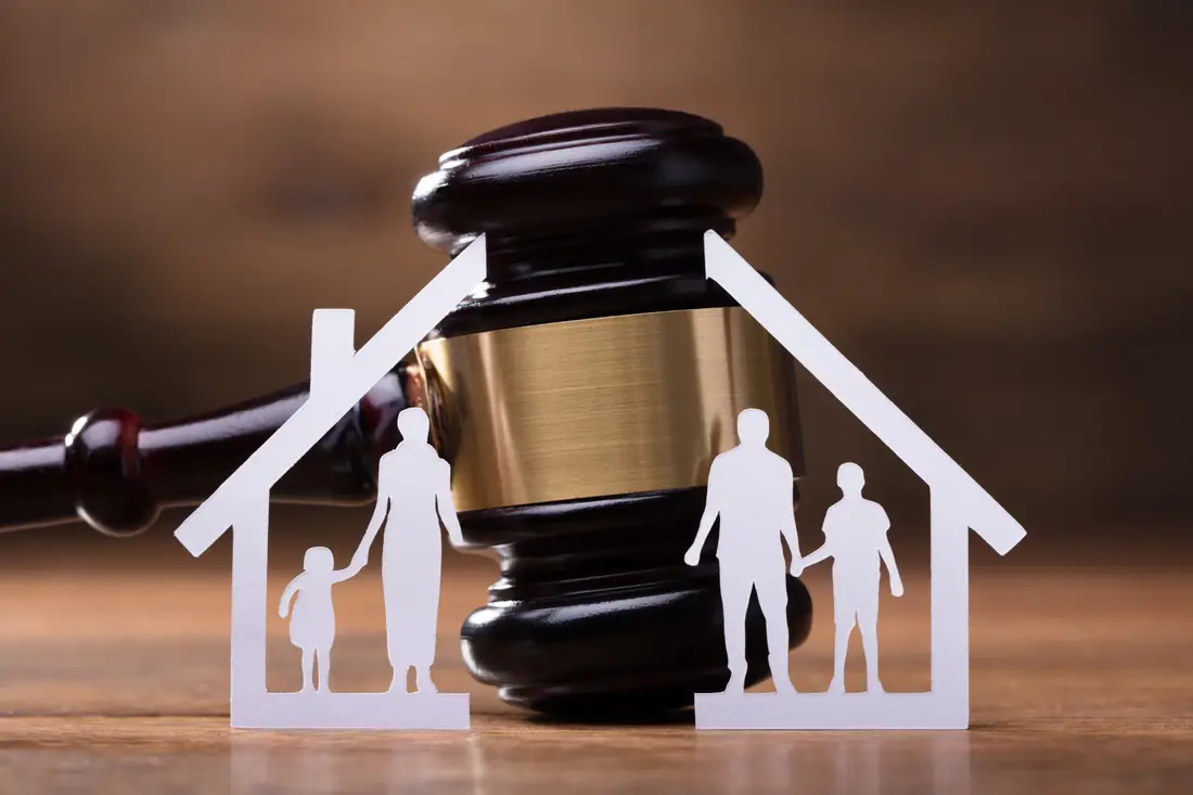 Paper family figures in a divided house in front of a gavel