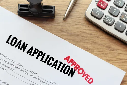 Loan application stamped approved beside a calculator