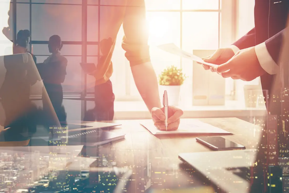 Business people signing papers in a bright office
